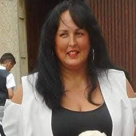 A middle aged woman with long dark hair wearing a white and black top.